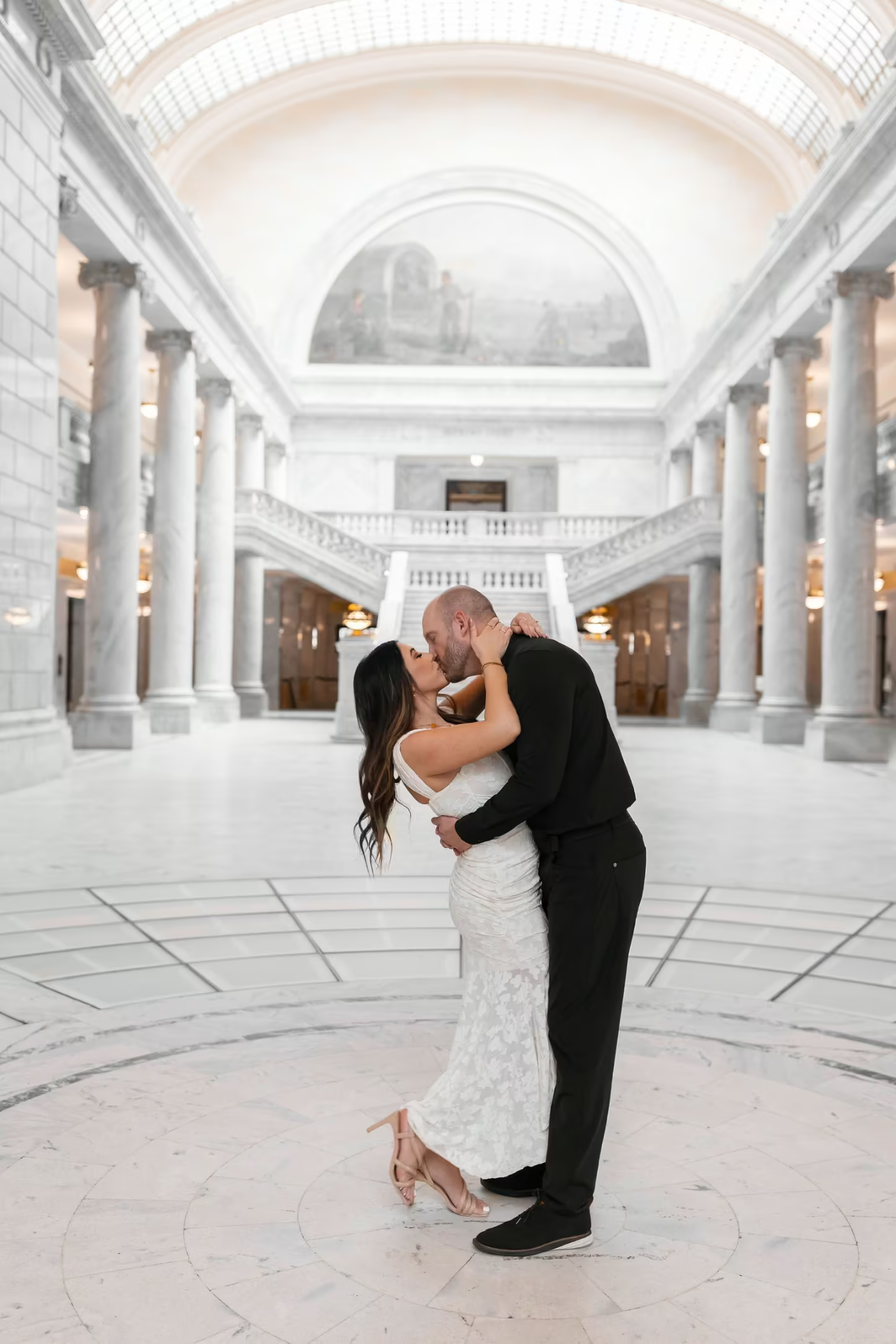 Travis and Chrissy kissing beneath the grand rotunda of the Utah State Capitol.