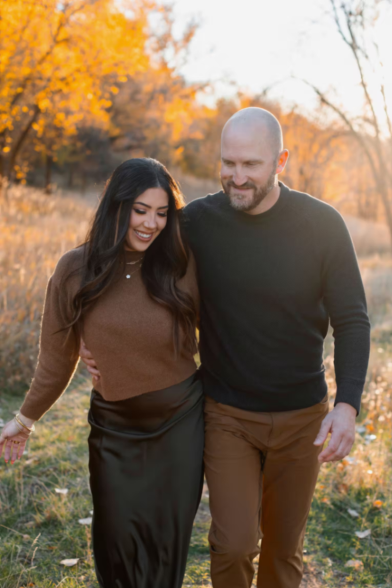 Travis and Chrissy walking together during golden hour in autumn.